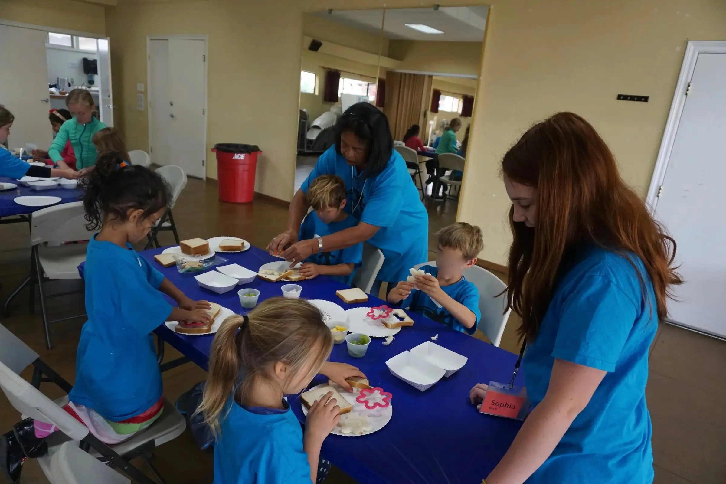 Kids in matching blue shirts working on craft projects at a long table in the fellowship hall