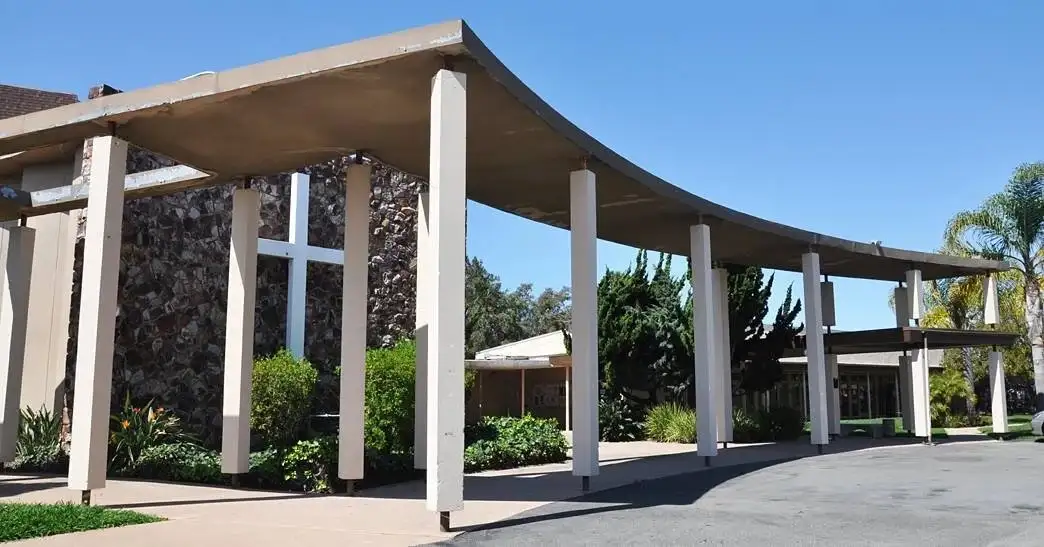 The curved, mid-century covered walkway leading to Northminster’s entrance on a sunny day