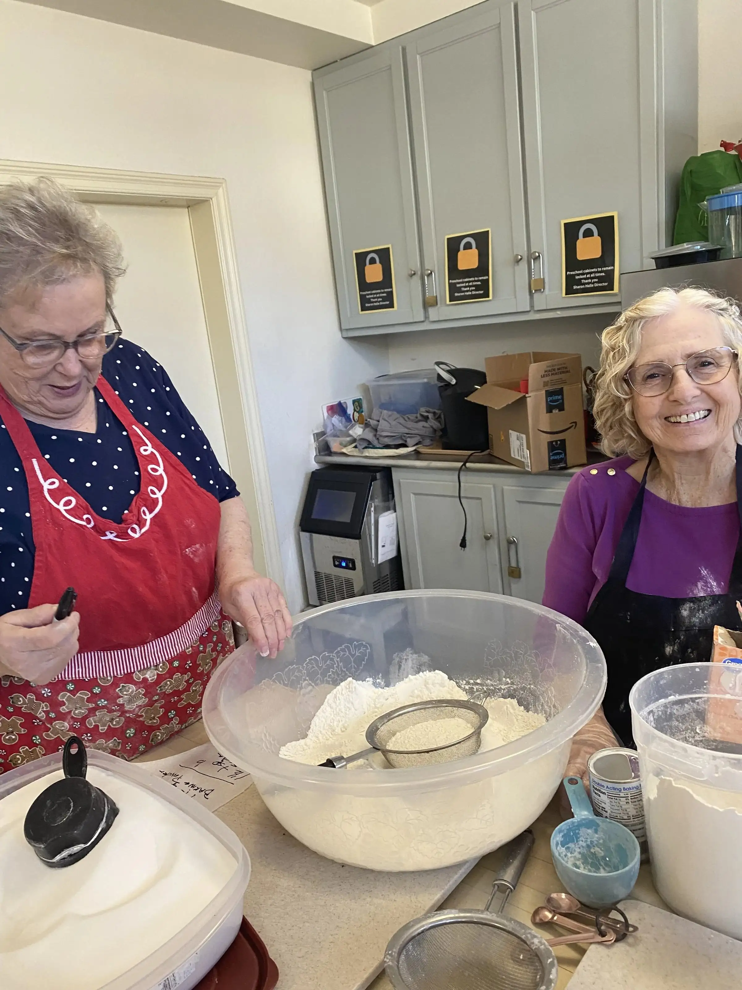 Two women smiling as they bake together in the church kitchen