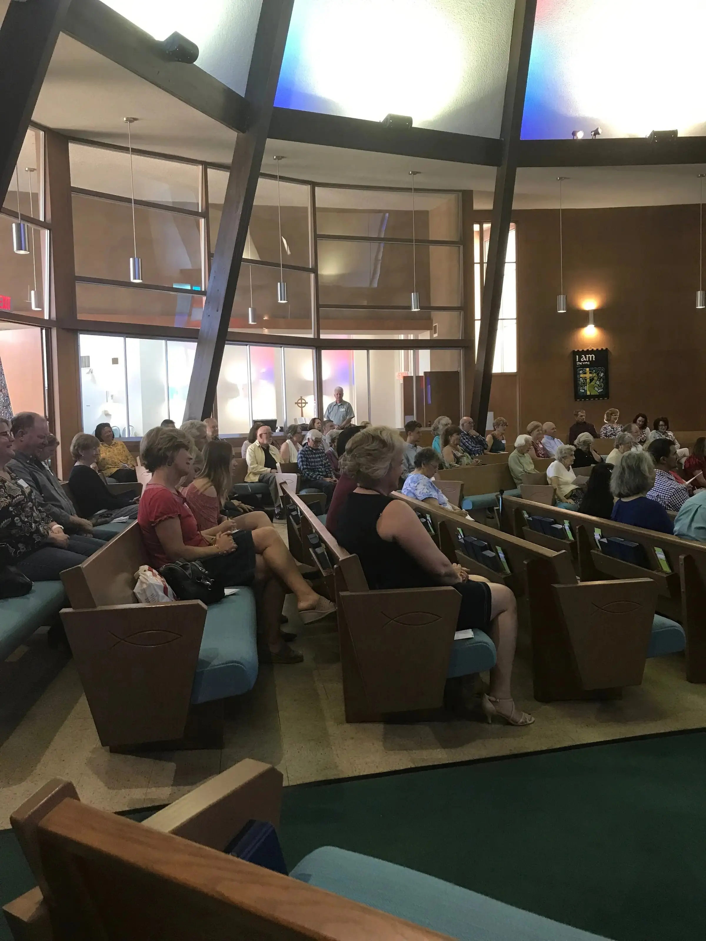 The Northminster congregation seated in the sanctuary beneath tall panels of stained glass