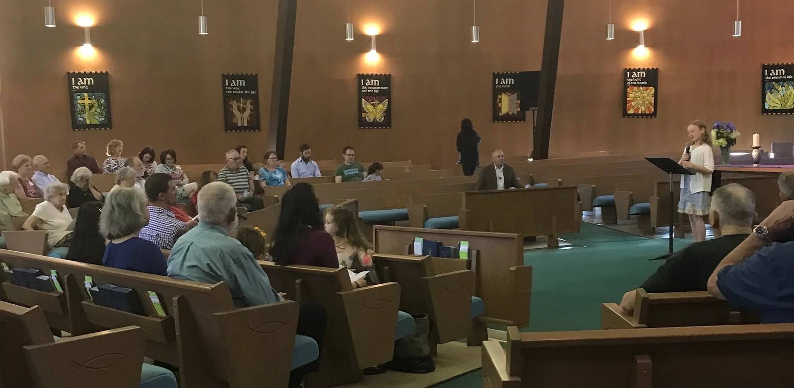 A young girl reads scripture at the lectern while the Northminster congregation listens from the pews