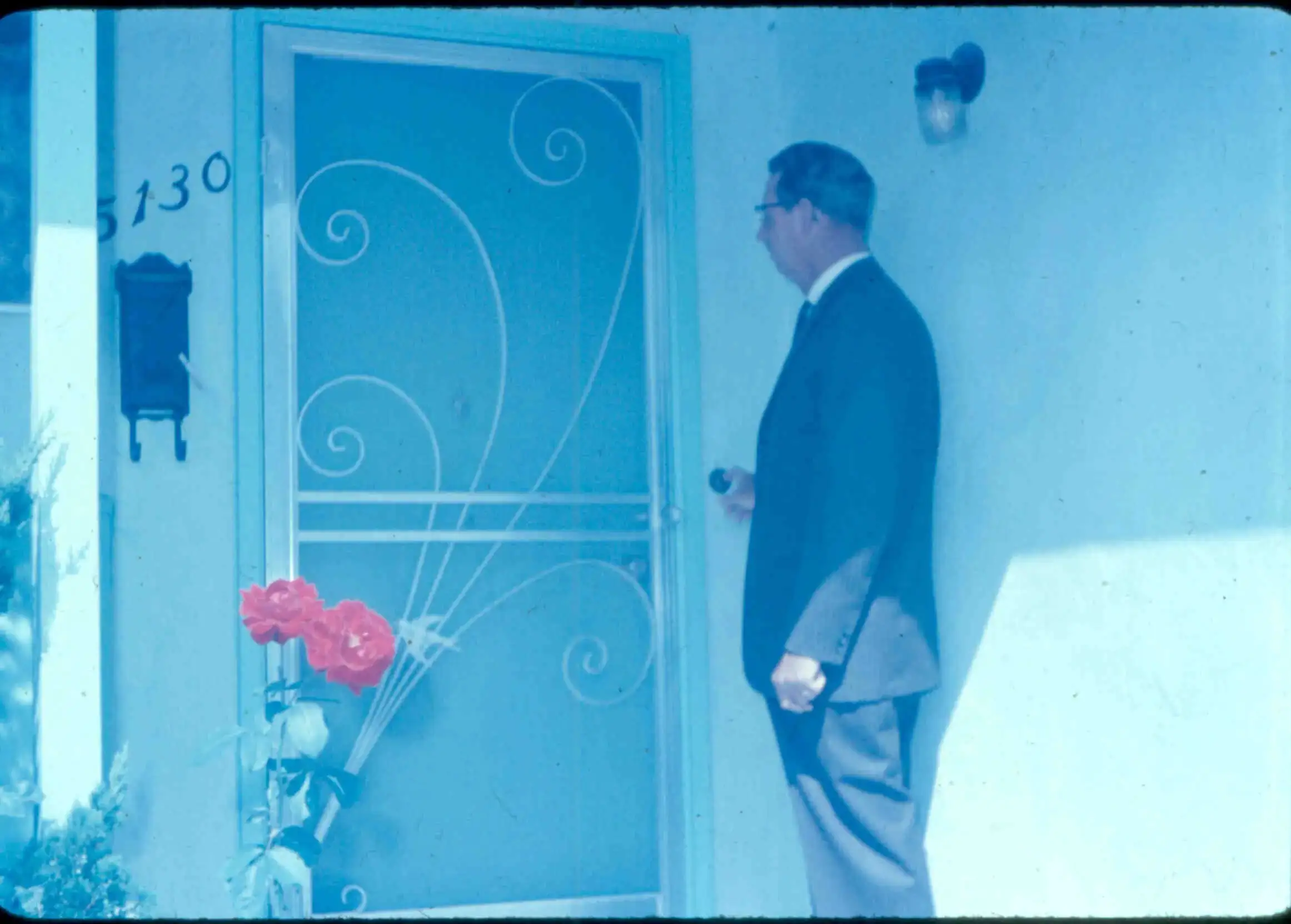 Rev. Howard Congdon standing at the door of a home in a dark suit