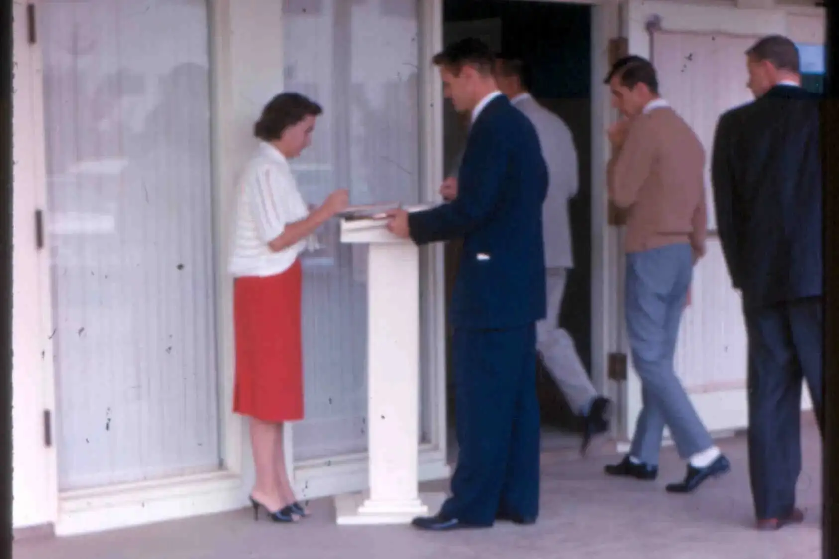 Olive Thompson greeting men in suits at the church door in 1962